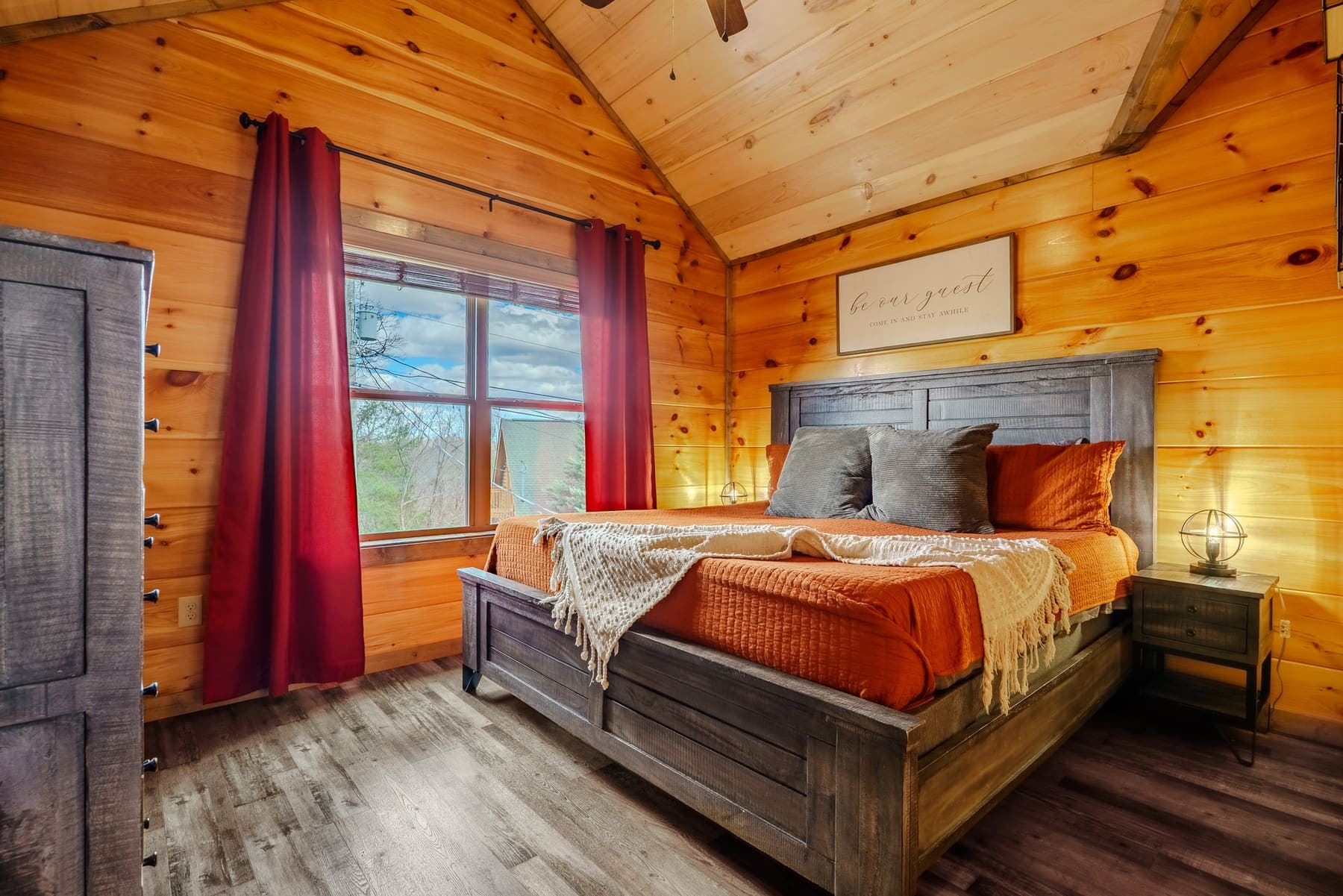 Vaulted king bedroom with gray-wood frame and burnt-orange quilt