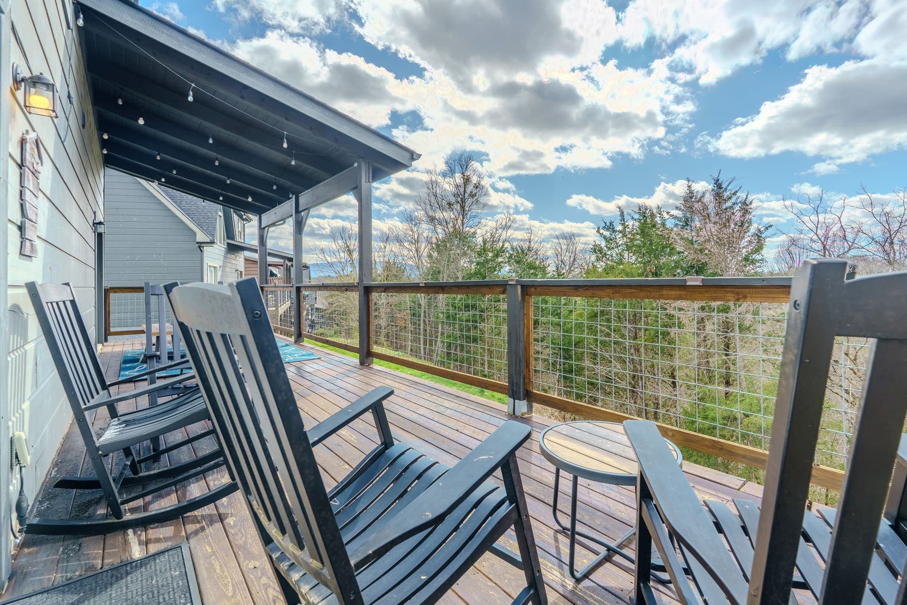 The lodge’s long deck run — rocking chairs in a row under string lights, the woods dropping away beyond the rail