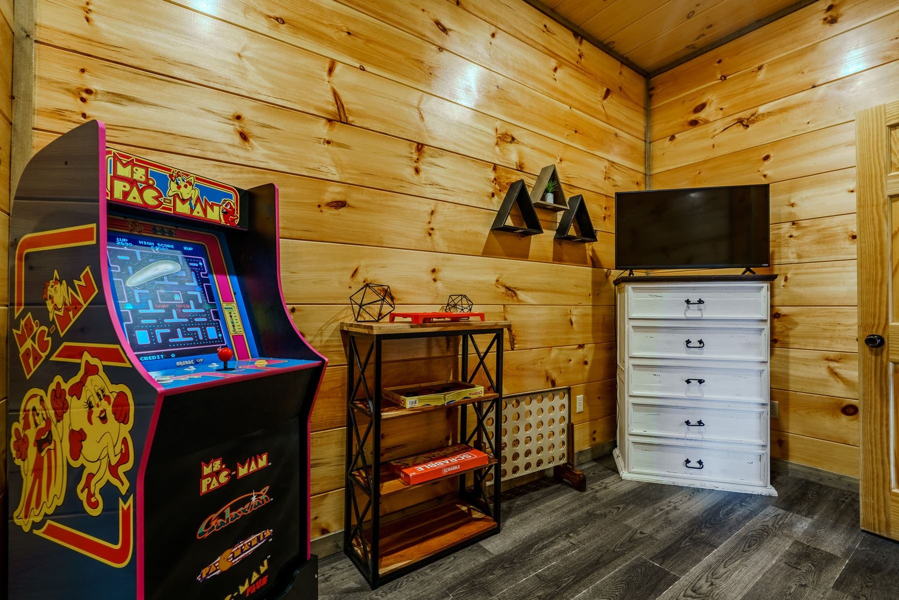 Game room corner — arcade cabinet, board-game shelf, and Connect Four