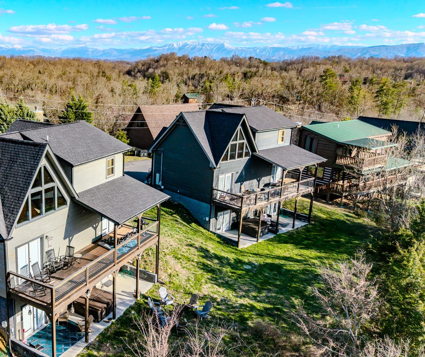 Aerial of the lodge’s prow-front gable and stacked decks, the snow-dusted Smoky Mountains on the horizon