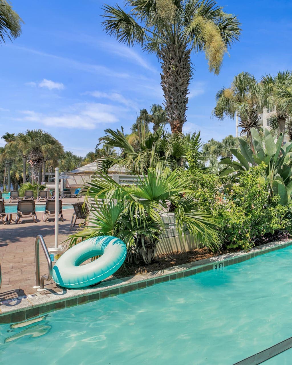 The lazy river curving past palms and a turquoise float beneath the condo towers at Destin West