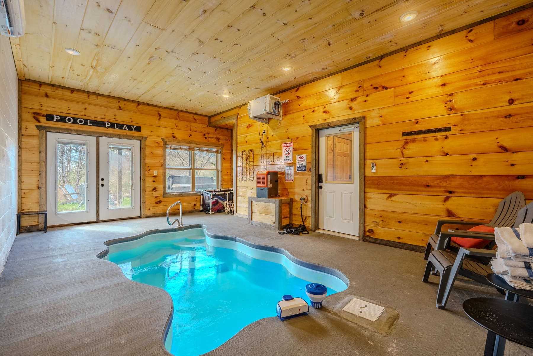 The indoor pool room — glowing freeform pool under knotty-pine walls and the ‘Pool Play’ sign