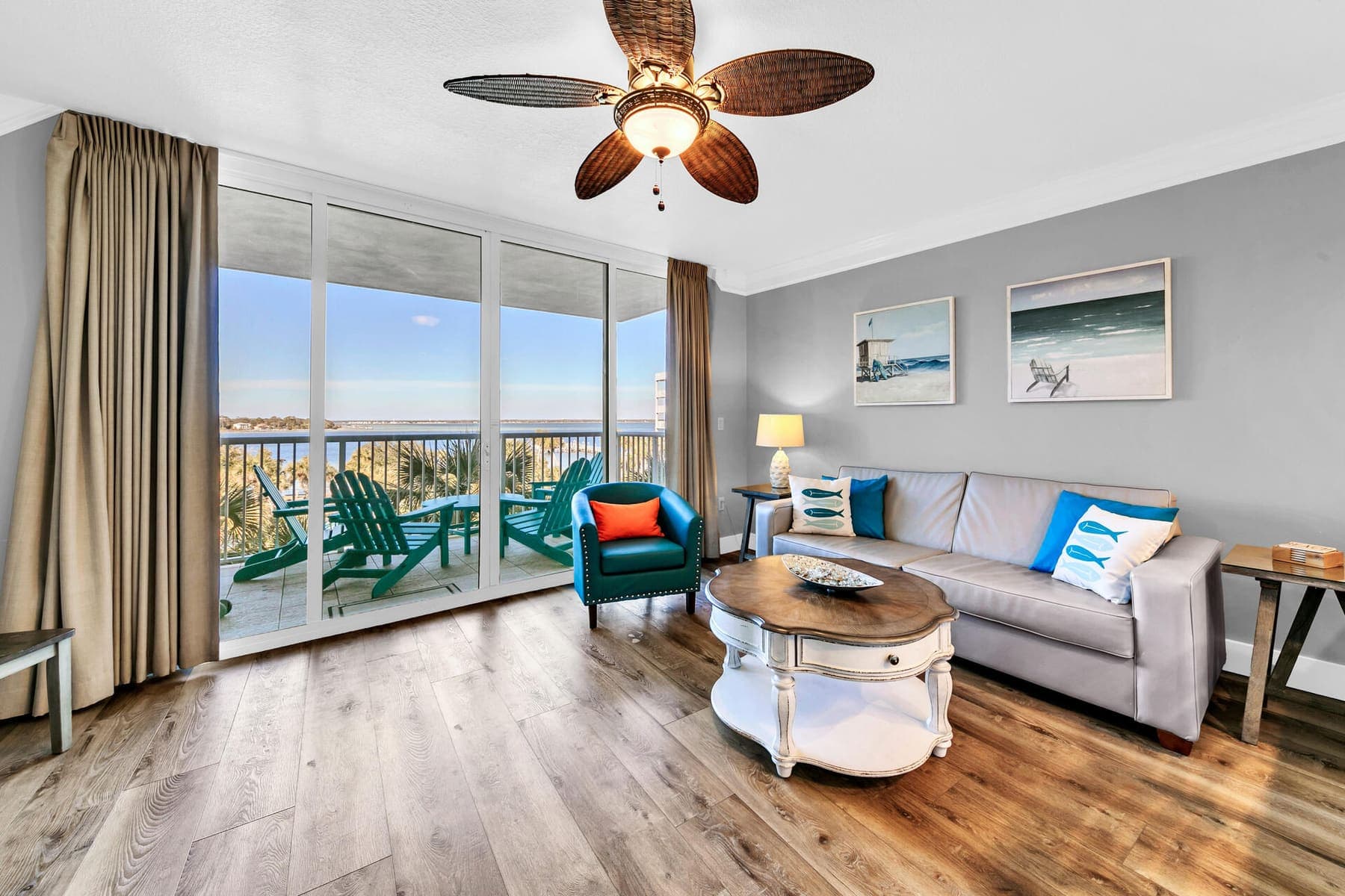 A living room made ready — sliders open to the balcony chairs and Choctawhatchee Bay beyond