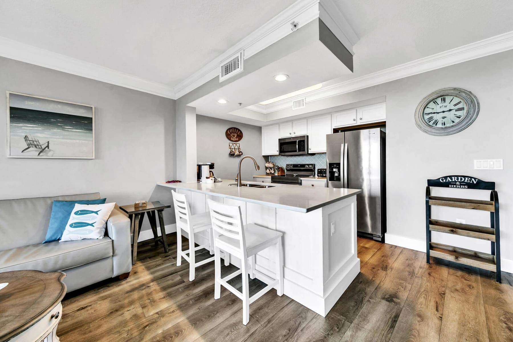 White kitchen island with bar stools and stainless appliances