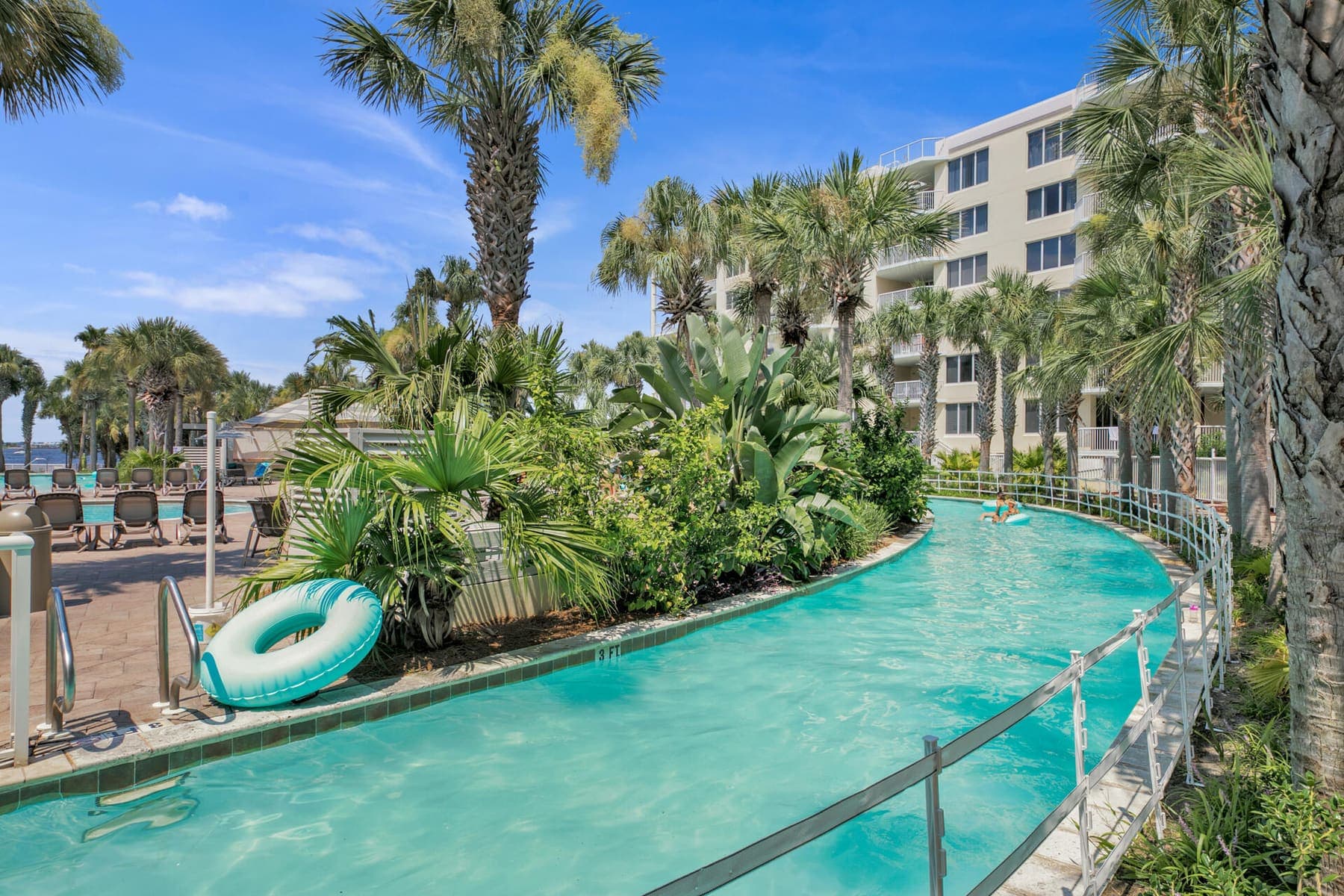 The lazy river sweeping past a lush planted island, a turquoise float drifting at its edge